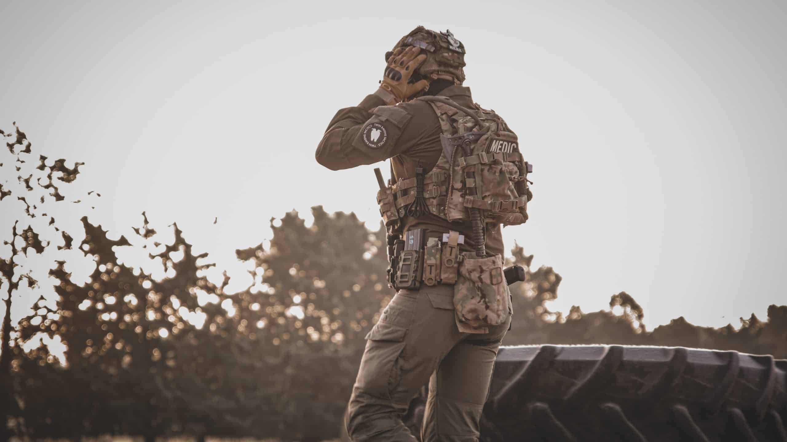 Jugador de airsoft a contraluz al atardecer en un campo abierto