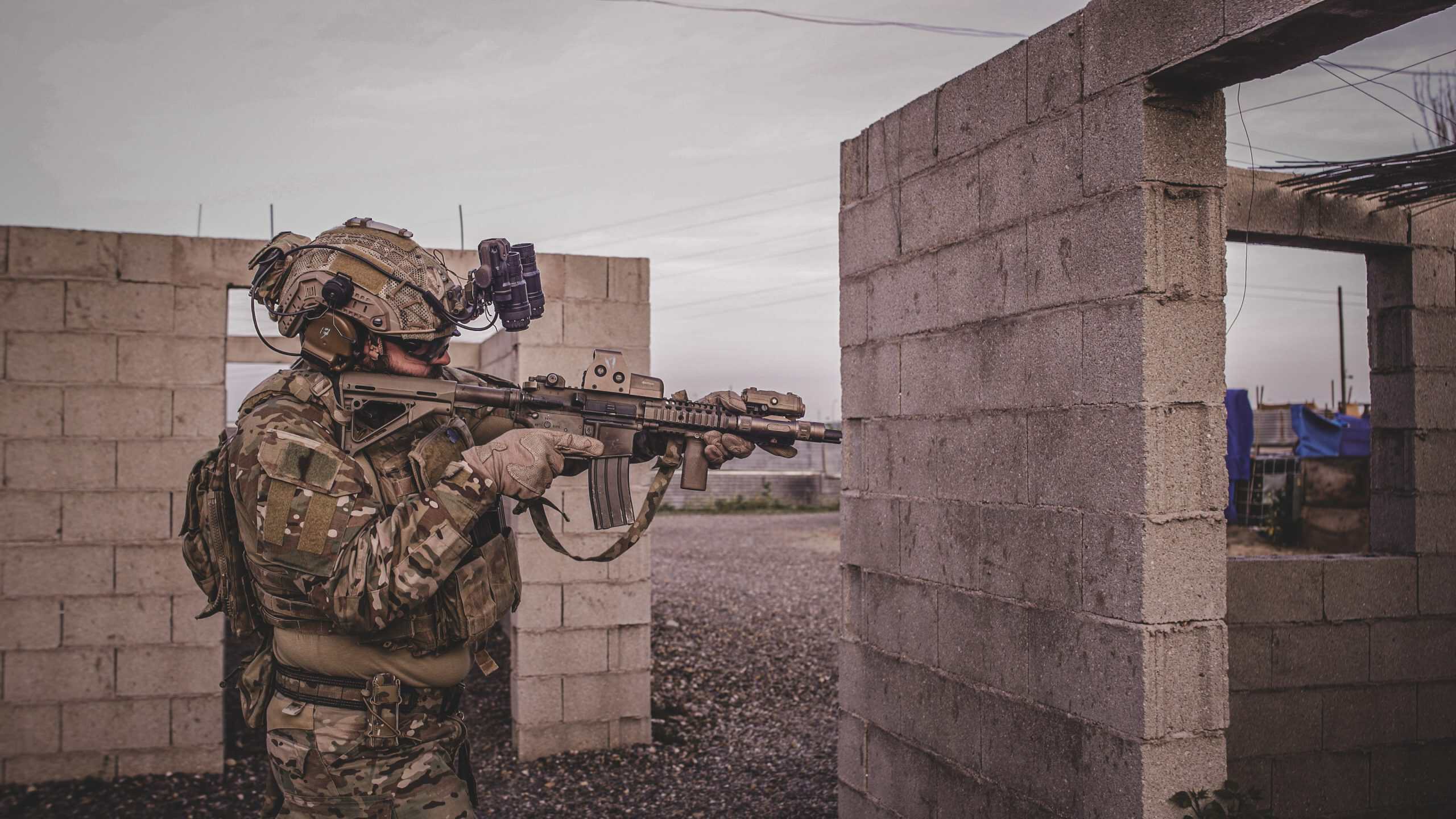Jugador de airsoft con visor nocturno apuntando entre muros de bloques de hormigón