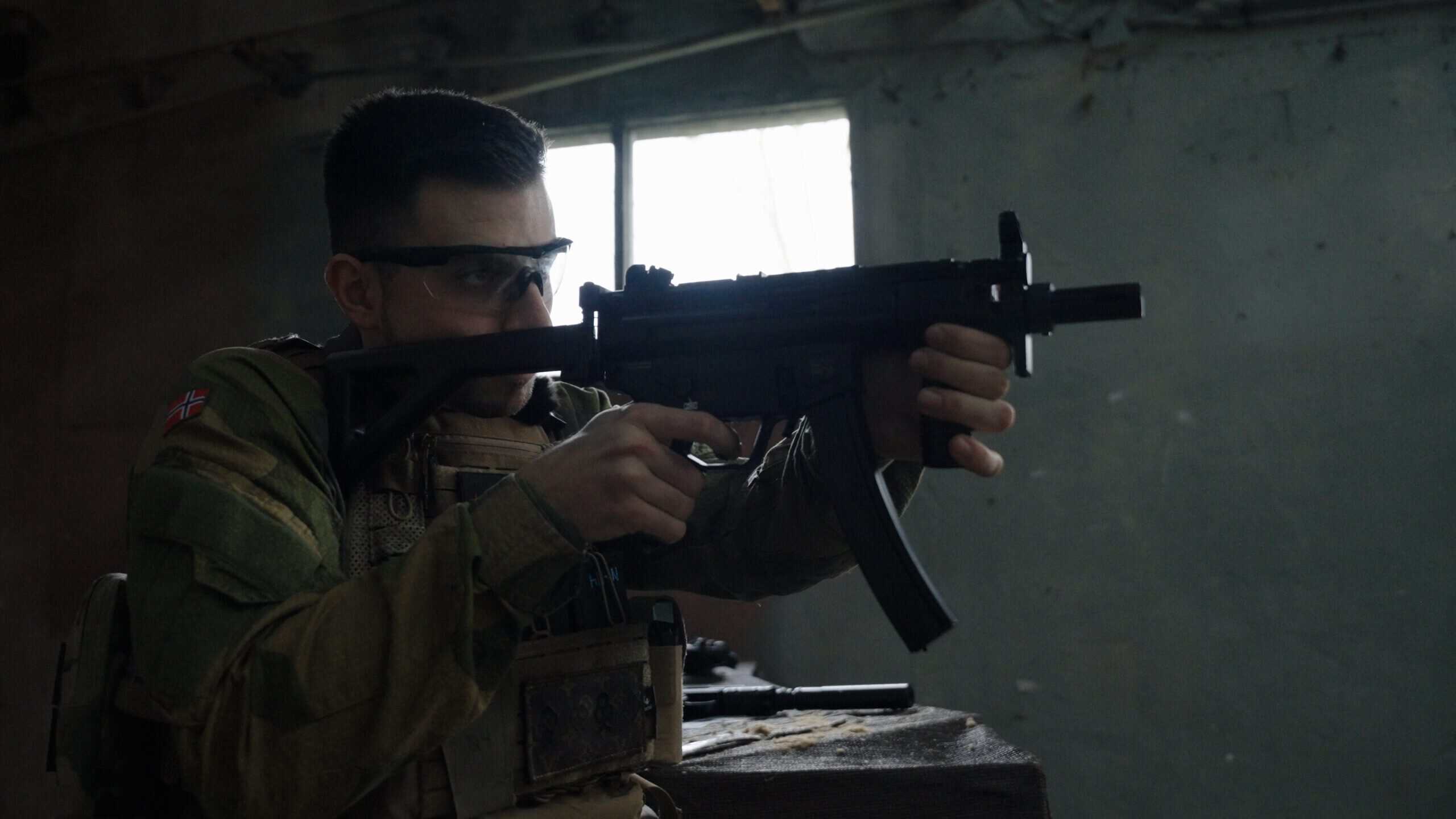 Jugador de airsoft apuntando con una réplica de MP5 dentro de un edificio