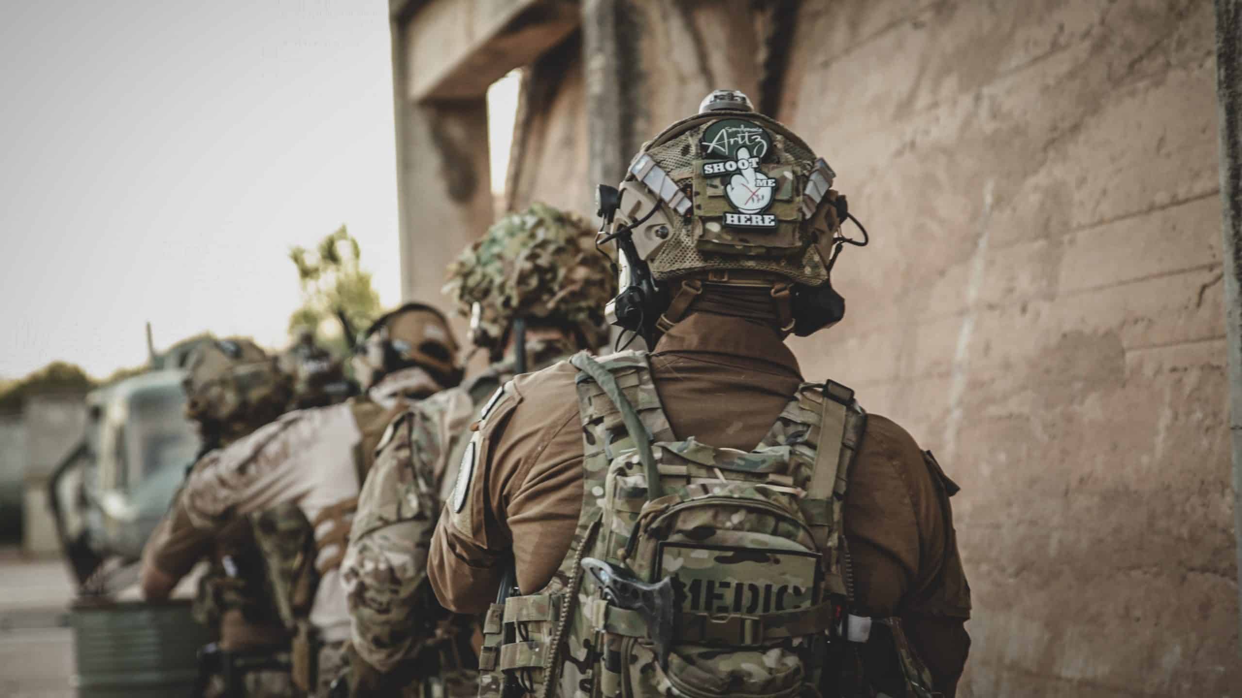 Equipo de airsoft apilado junto a un muro antes de entrar a un edificio