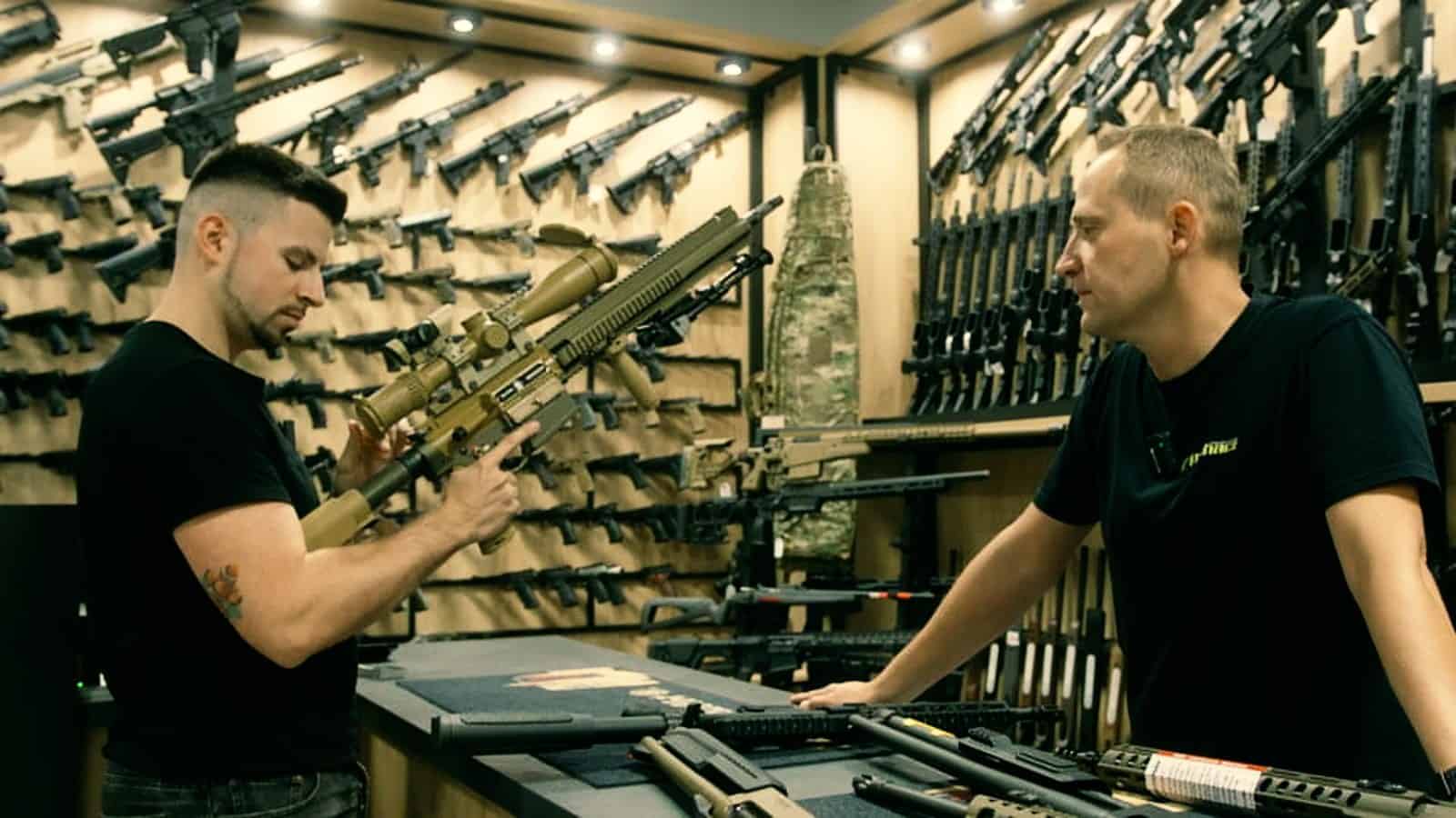 Aritz en una armería de Polonia con las paredes llenas de fusiles y pistolas