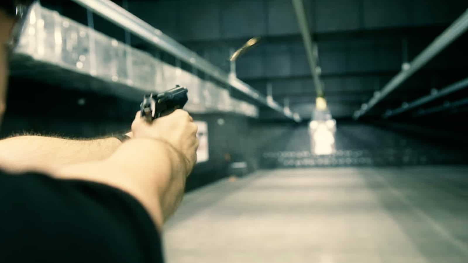 Disparando una pistola en una galería de tiro de Polonia, con la vaina en el aire