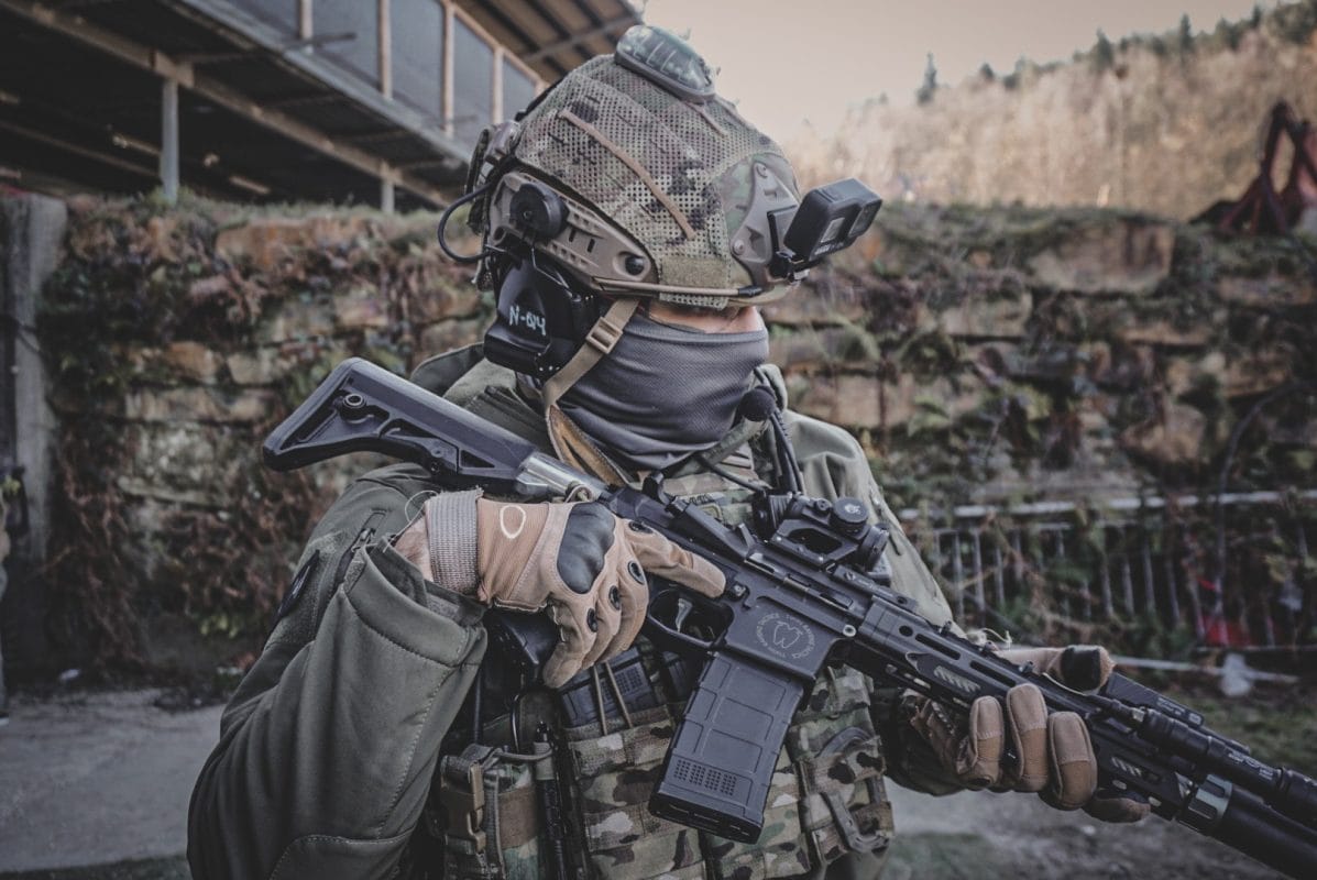 Jugador de airsoft con réplica M4 y cámara en el casco
