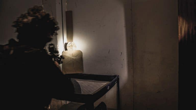 Linterna iluminando un blanco de silueta en una sala a oscuras