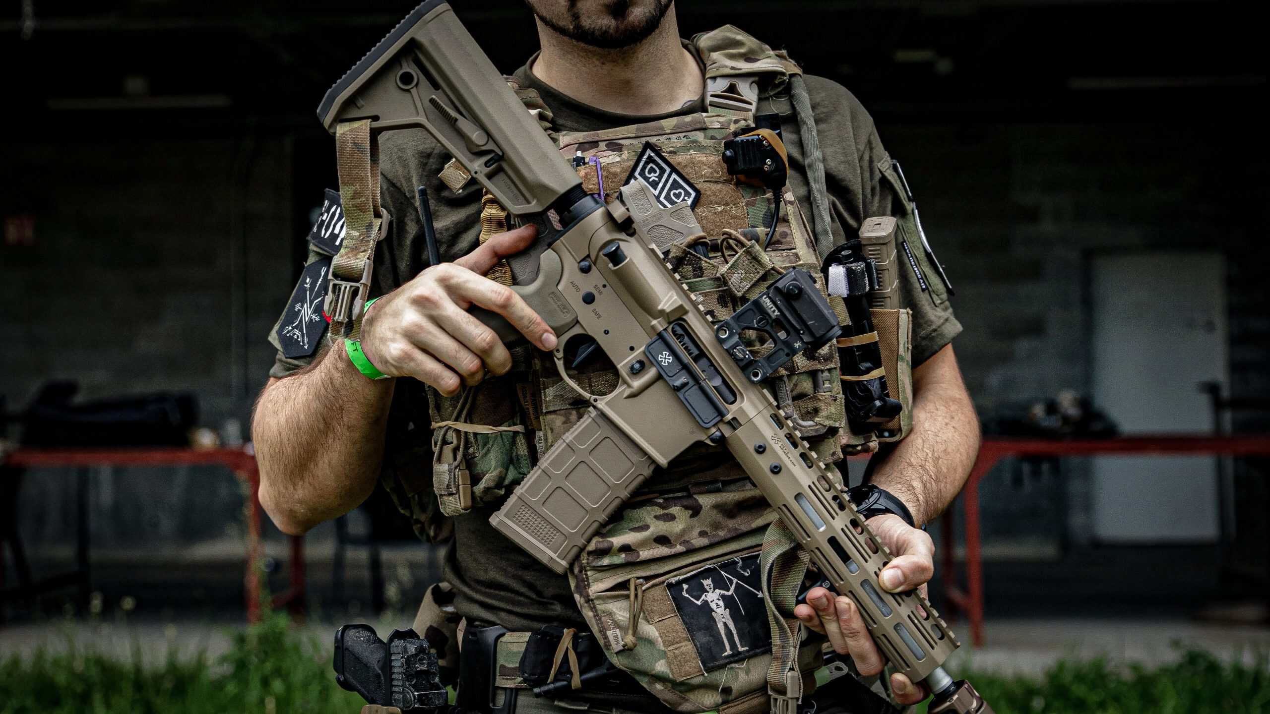 Jugador de airsoft con el portaplacas cargado y una réplica M4 completamente equipada